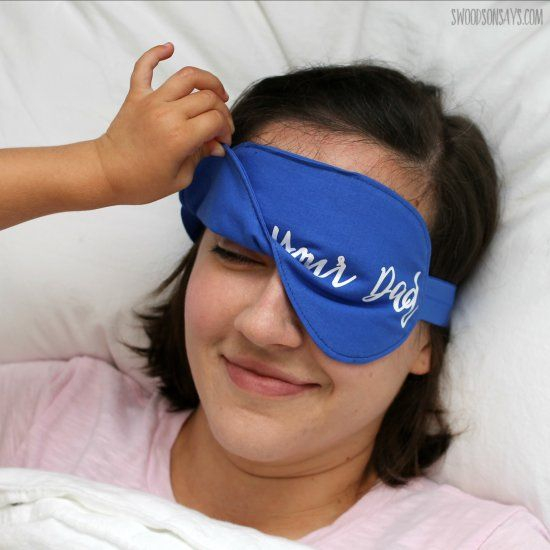 A Woman Laying In Bed With A Blue Sleeping Mask On Her Face That Says 